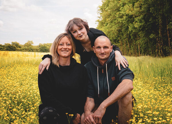 Madeleine Roediger, Olivier Monnet et Manon Monnet-Roediger en pose pour une photo au milieu des prés fleuris de Terre de Rêves au coeur de la Dombes